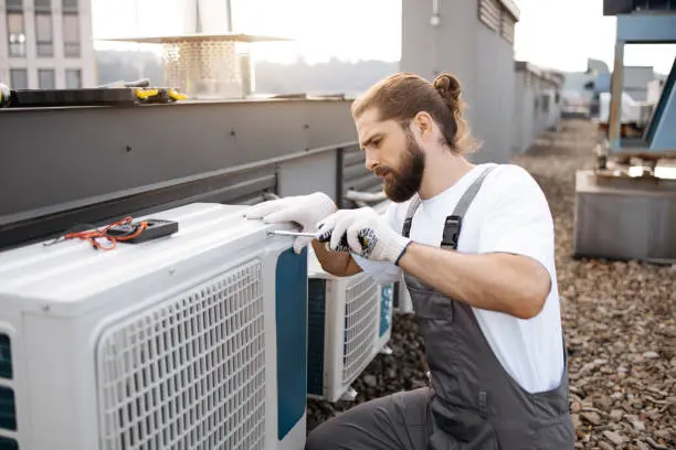 Técnico especializado trabajando en unidad exterior de aire acondicionado con herramientas — reparación de compresor